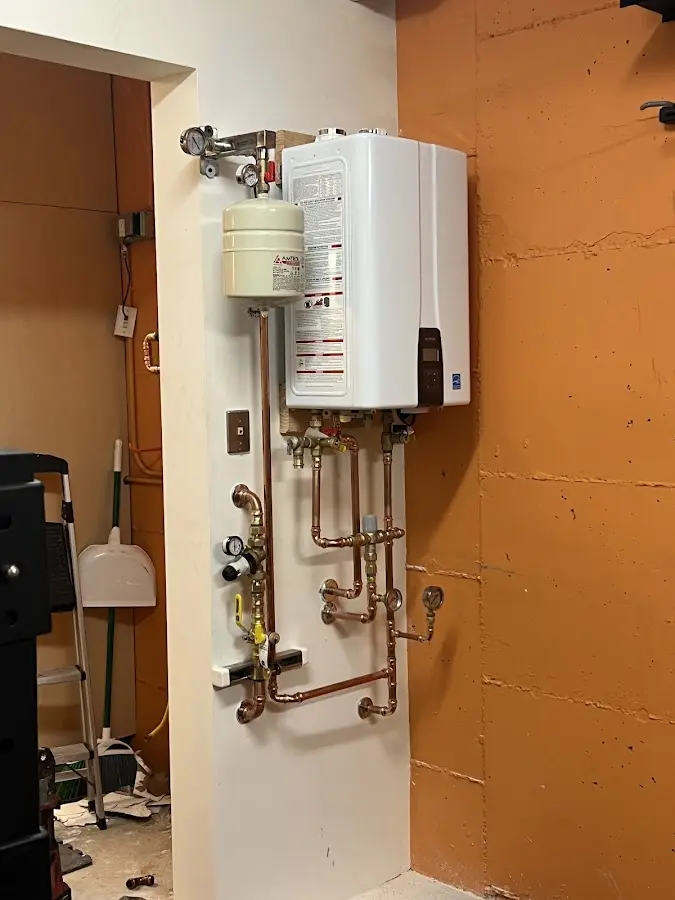 Plumbing technician inspecting water heater connections in Lemay